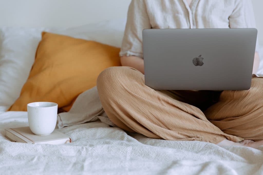 Woman sitting on bed using laptop