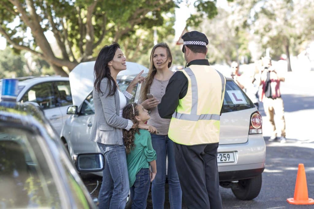 Two women involved in a car accident giving their statements to a police officer.