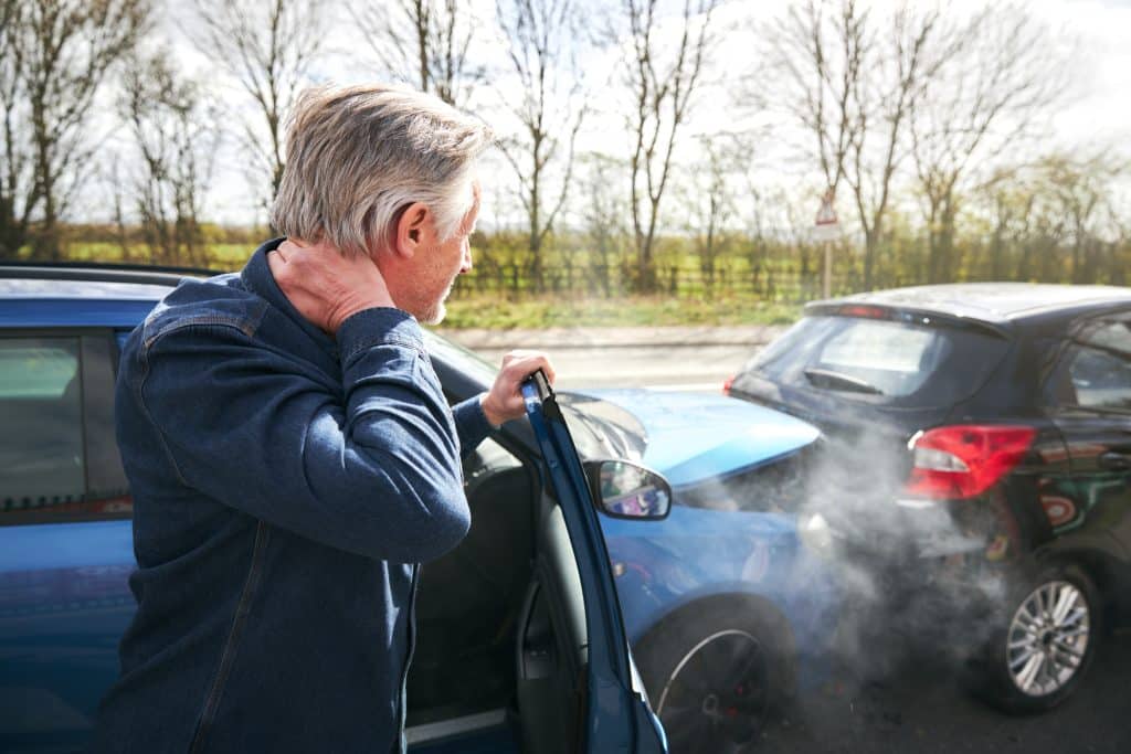Man rubbing his injured neck after a car accident.