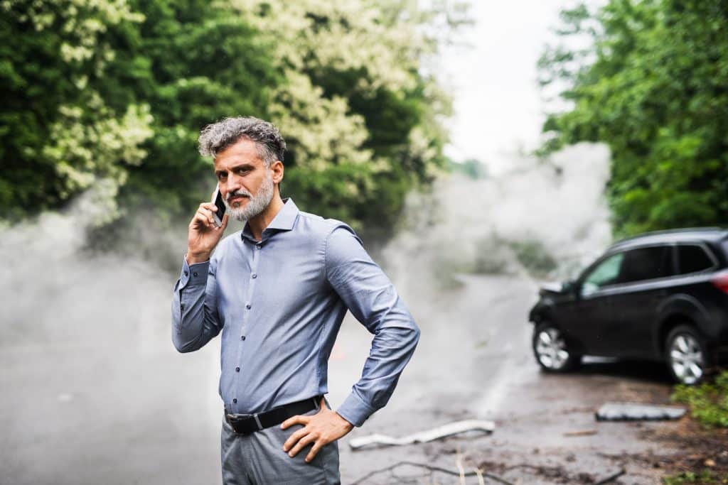 A man on his cell phone after an accident in a rental car.