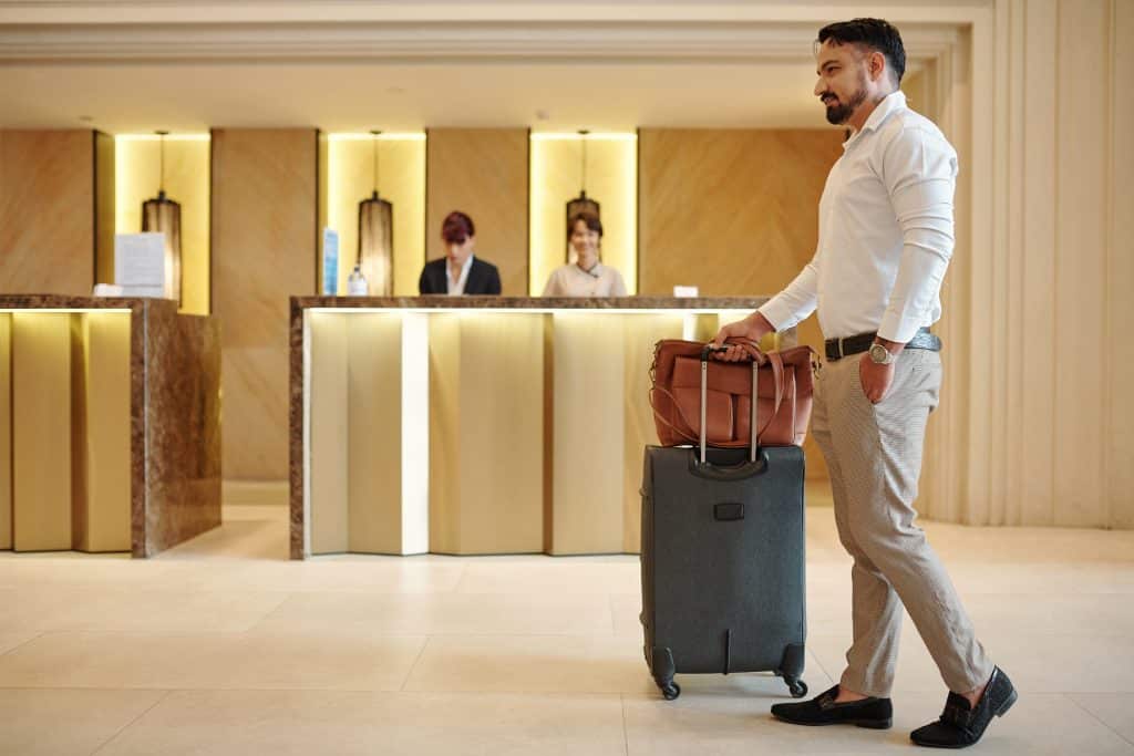 Man with briefcase and suitcase entering lobby of expensive hotel
