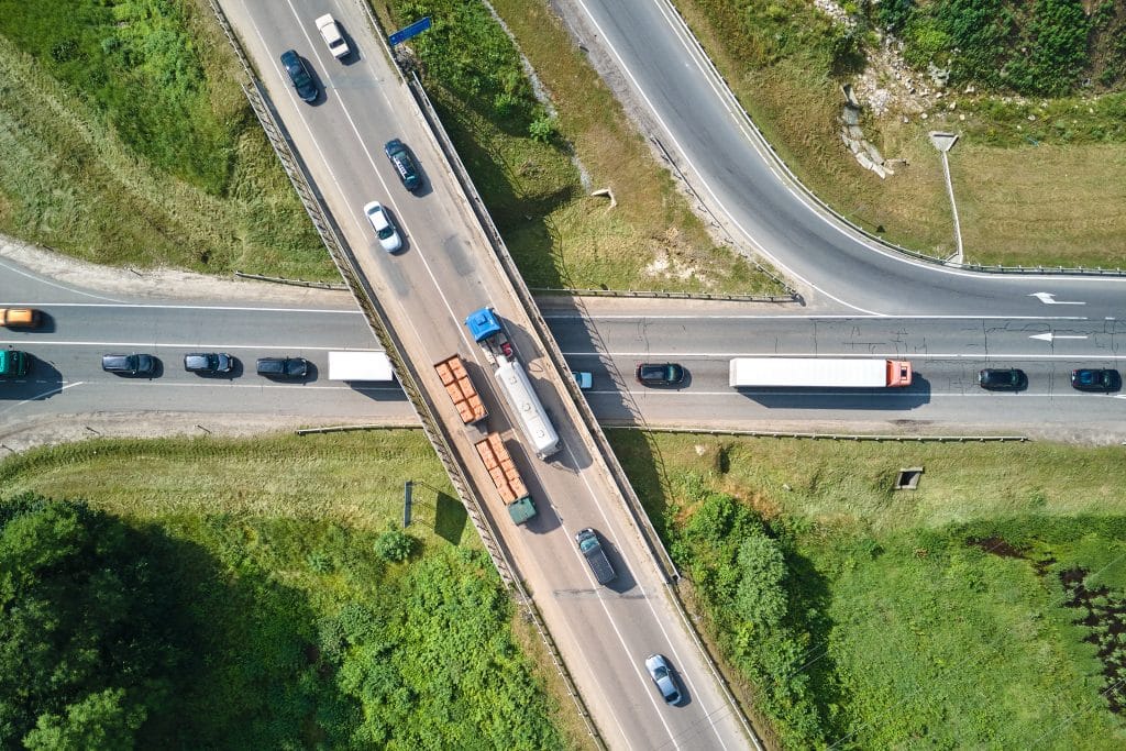 An aerial view of a busy intersection with large commercial trucks sharing the road with passenger vehicles.