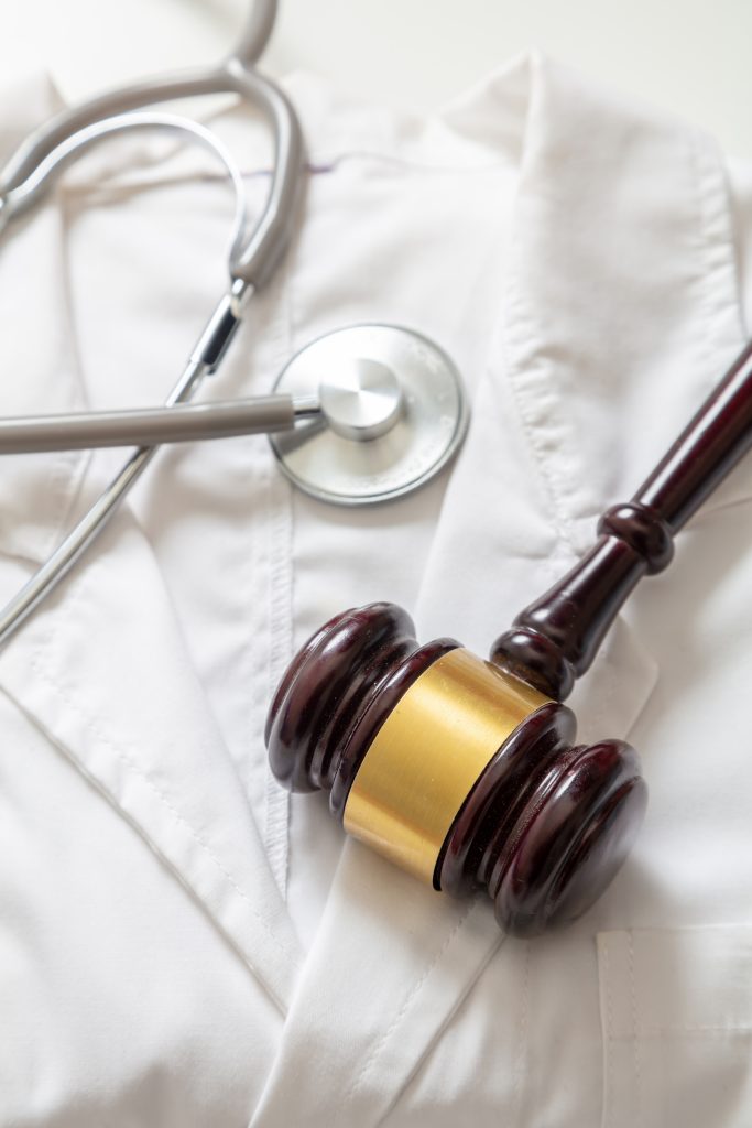Judge gavel and stethoscope on doctor coat