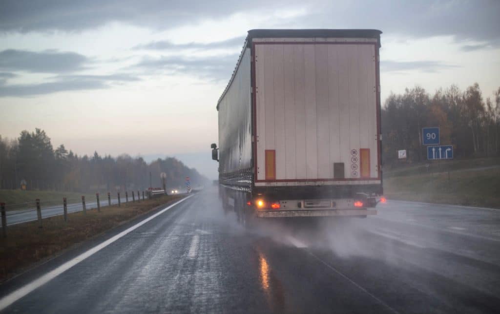 A commercial truck changing lanes in rainy weather