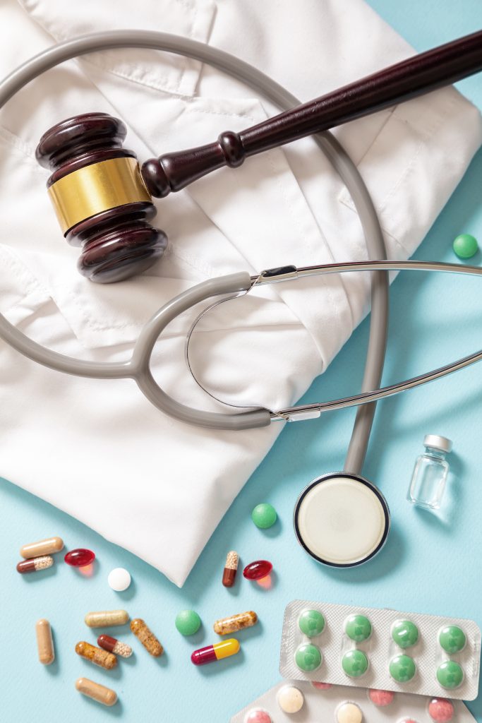 Judge gavel, stethoscope and medication on doctor coat