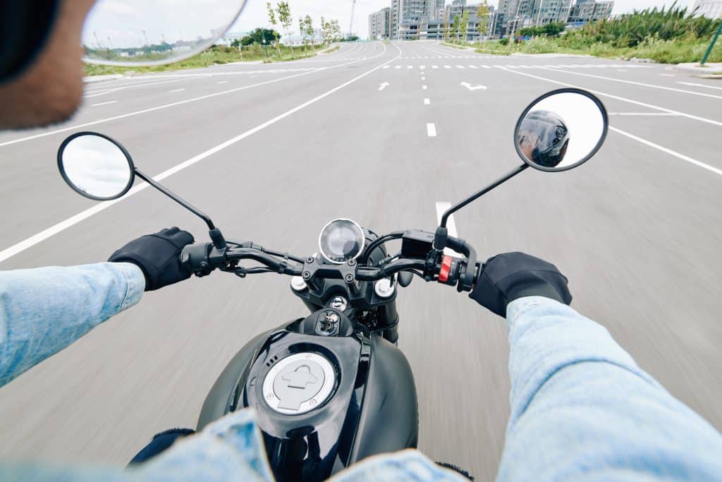 View over handlebar of motorcycle of young man riding fast on highway