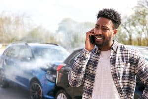 Young man calling insurance company from scene of accident