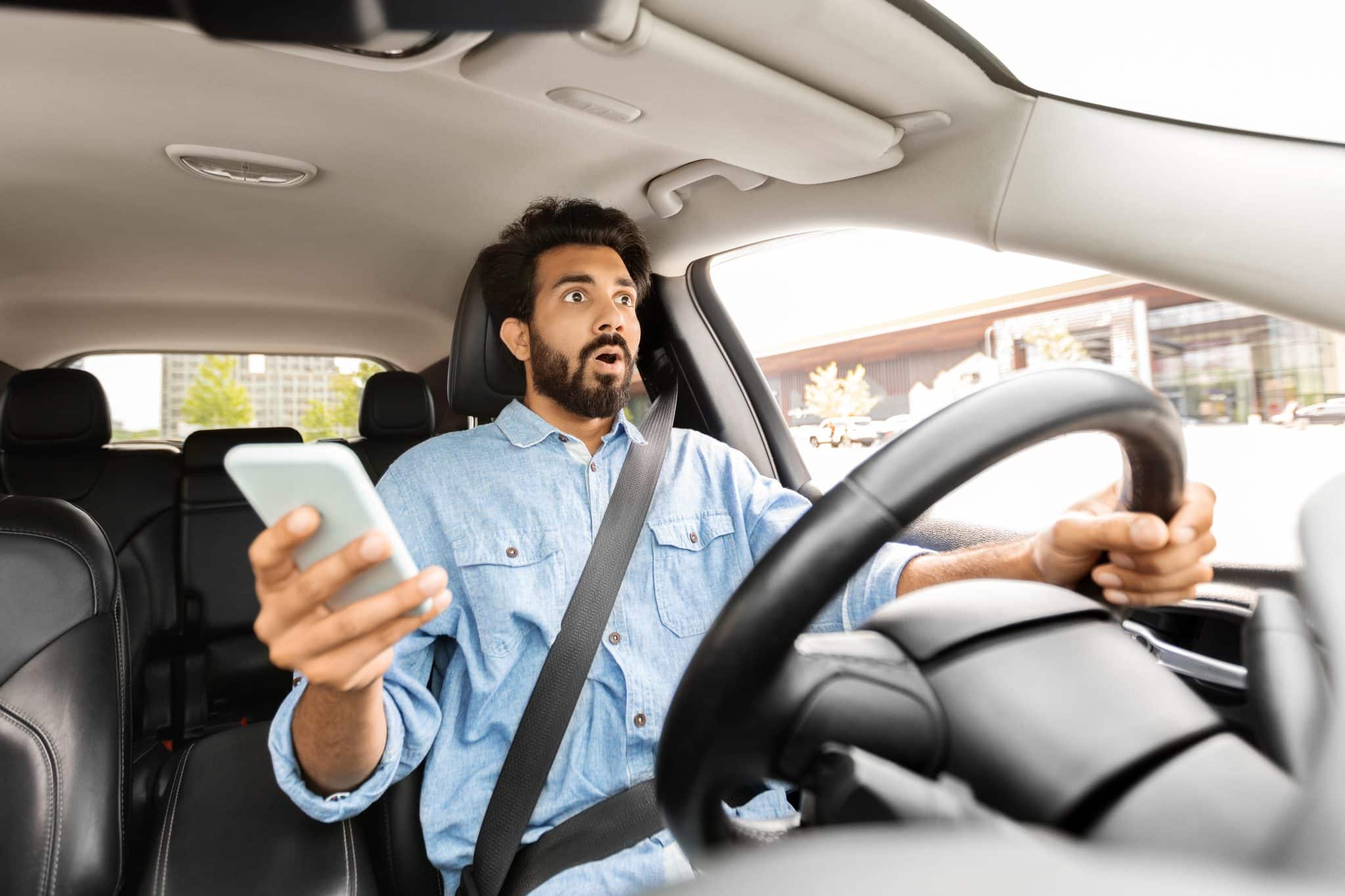 man driver using smartphone while driving car