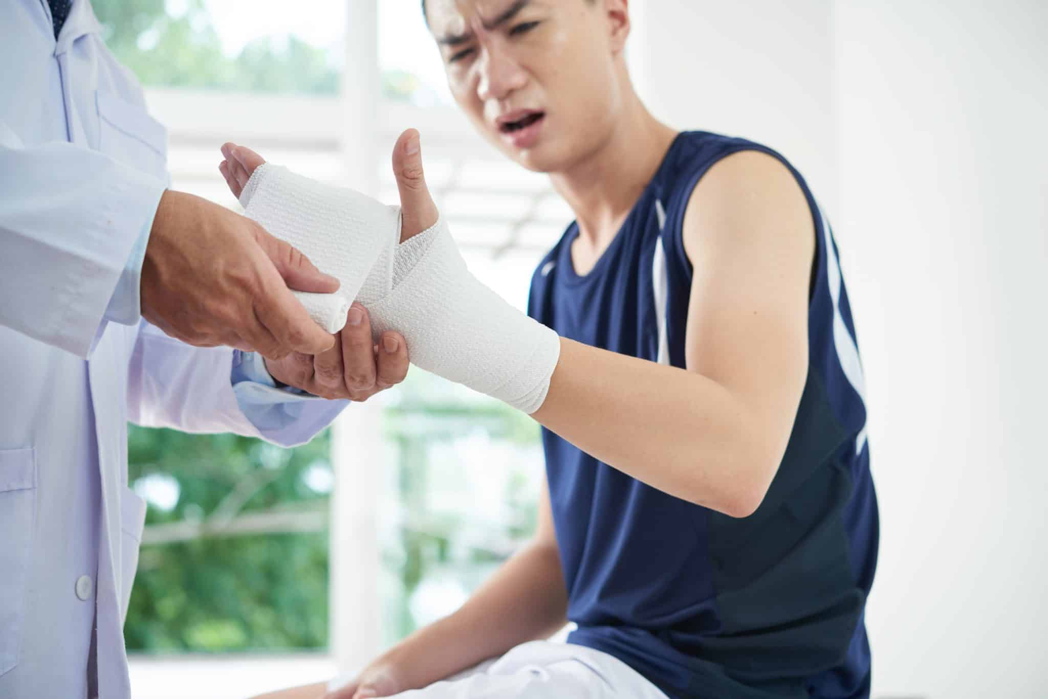 doctor bandaging hand of man