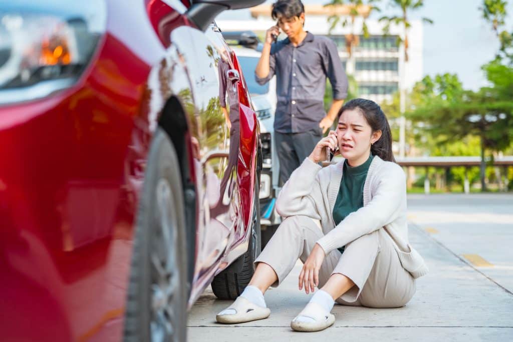 Woman on phone next to damaged car