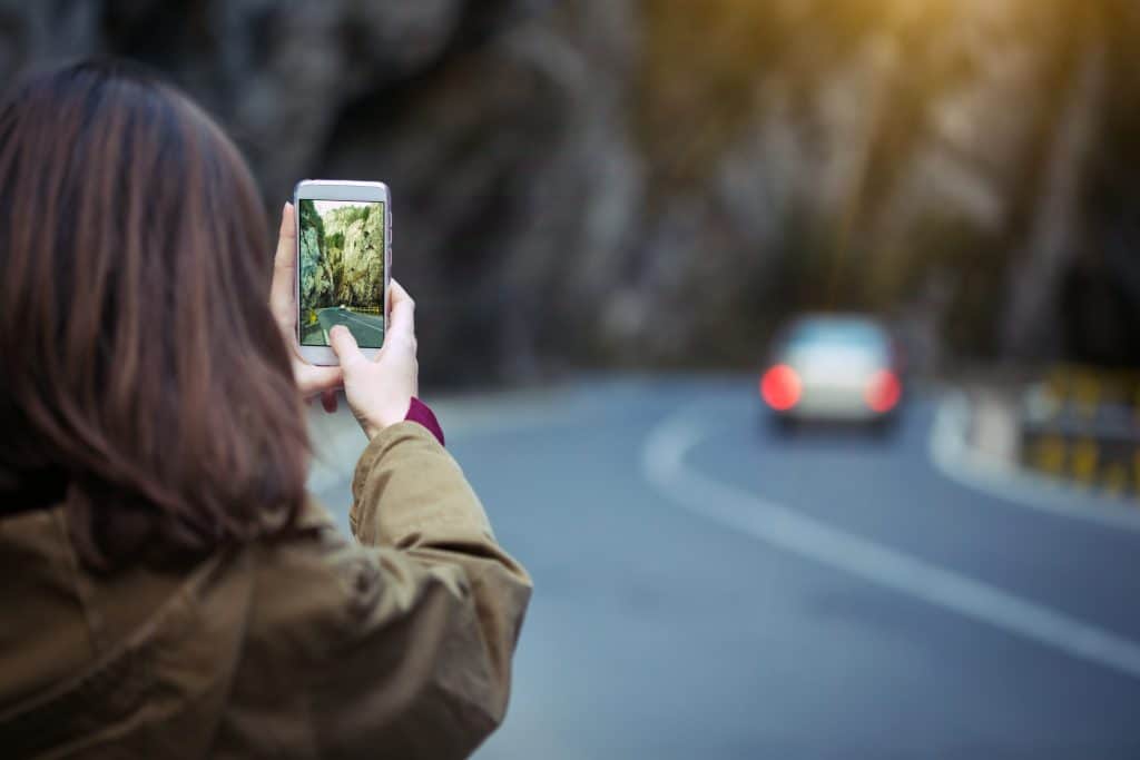 woman taking photo of fleeing car