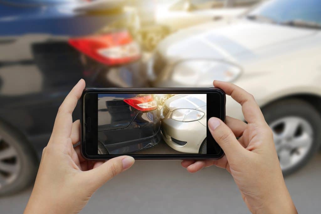 Close up of hands using phone to take picture of accident